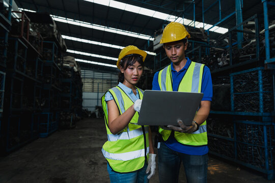 Warehouse workers using laptop for inventory management in industrial storage