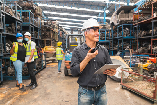 rofessional supervisor in mask using radio and tablet in automotive spare parts warehouse