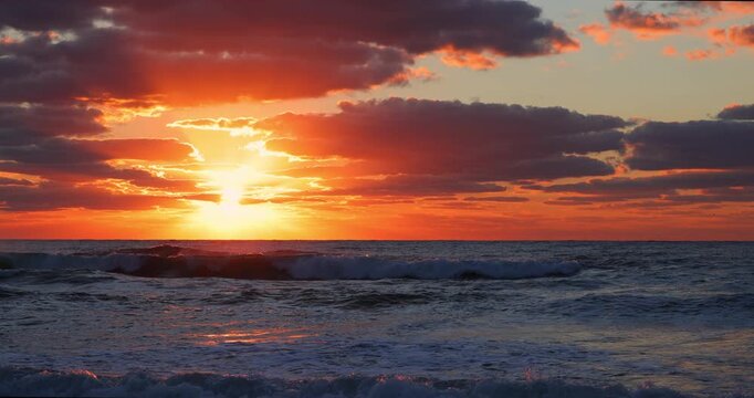 Bright sun rising over calm ocean waves with orange clouds nature  background