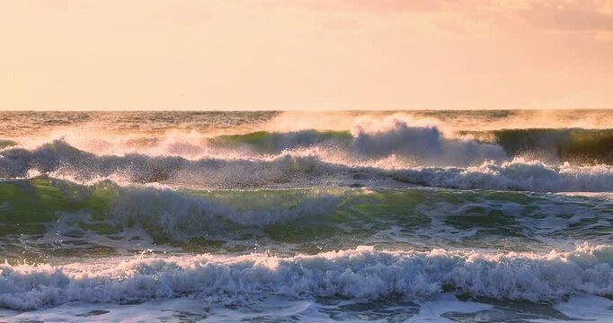 Ocean waves rolling on the sea sand toward sandy beach at sunrise