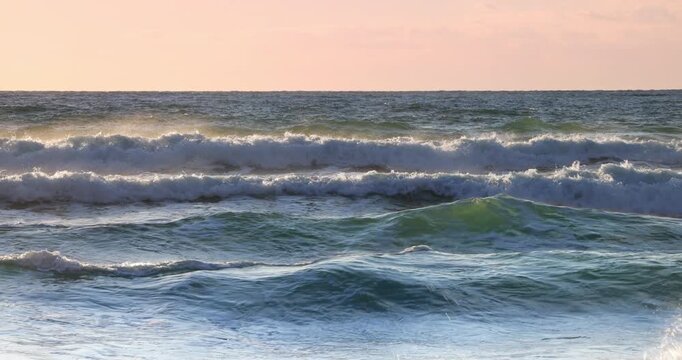 Sunset Ocean Waves Crashing On the beach shore With Golden Light And Rolling Sea Spray At Dusk