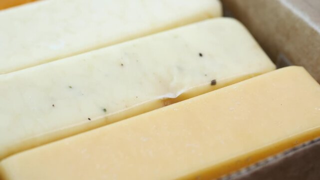Close up cinematic footage of various cheese bars in paper box ready for sale at market, gourmet food dynamic shot