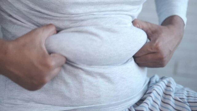 Woman showing her overweight belly in a close-up motion shot, highlighting issues of obesity and weight gain