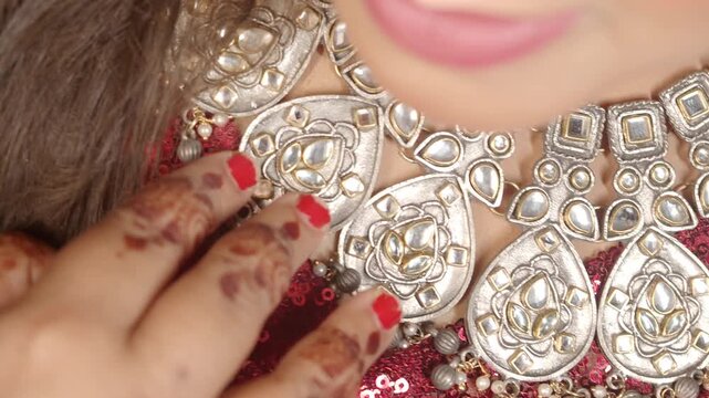 Woman wearing traditional heavy silver necklace with intricate kundan work and red bridal dress close up