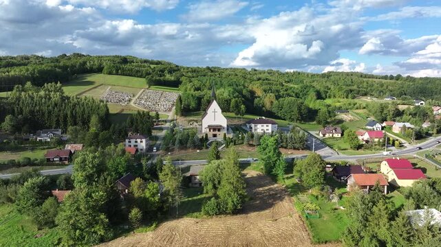 Aerial mountain village Lutcza church southern Pola. South eastern Poland. Historic mountain valley village with 15th century wooden All Saints Church. Agriculture land, rivers, forest and rural farm.