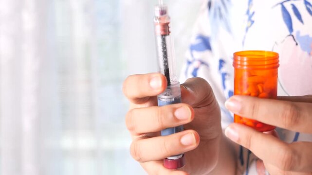Person holding insulin pen and pill bottle with pills inside diabetes medication concept