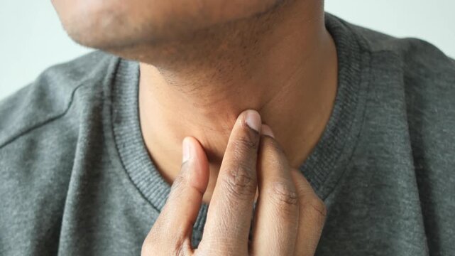 Young man touching sore throat and neck area feeling discomfort