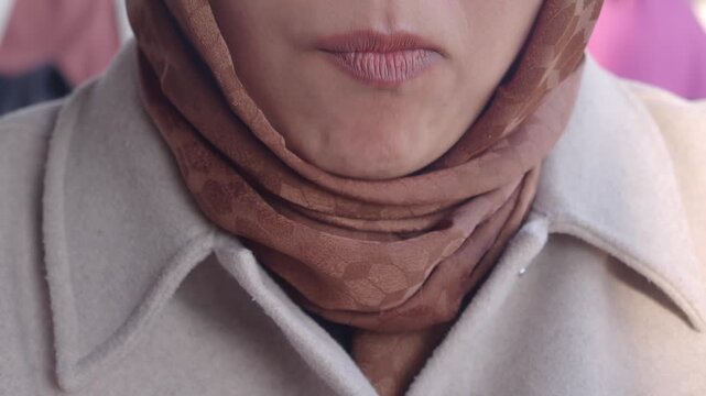 Middle eastern woman wearing hijab eating slice of fried turkish sausage sucuk with fork