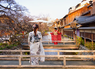Two young women wearing traditional white and red Japanese kimonos in the Gion district of Kyoto – Gion District, Japan. © muratart