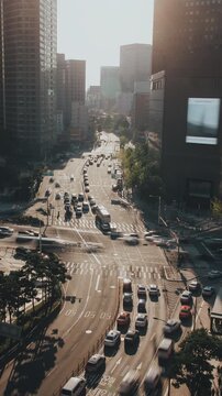 Busy urban intersection with vehicles navigating through traffic as sunlight illuminates the cityscape and buildings. Time-lapse, Seoul, South Korea