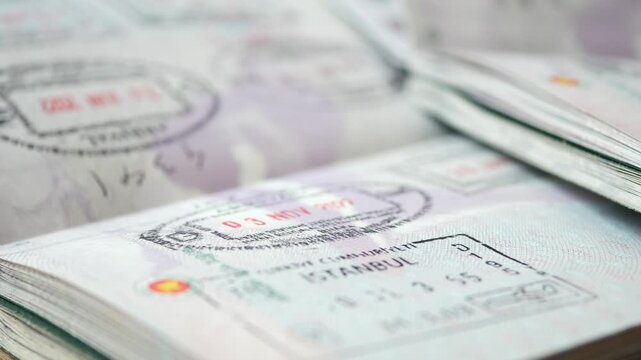 Close up motion shot of opened passport pages displaying various visa stamps and entry-exit markings from different countries, symbolizing international travel and global mobility