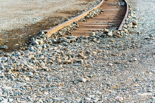 Disused and broken railway tracks disappearing into the stony ground as a conceptual metaphor for obstacles, failure, and blocked progress.