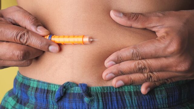 Young man using insulin pen for subcutaneous injection in stomach area for diabetes control