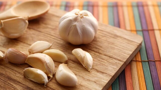 Whole garlic bulb and cloves on wooden cutting board, kitchen preparation