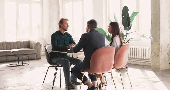 Diverse hiring managers team interviewing male applicant during talent acquisition process evaluating professional abilities and self presentation then shaking hands approving candidate for position