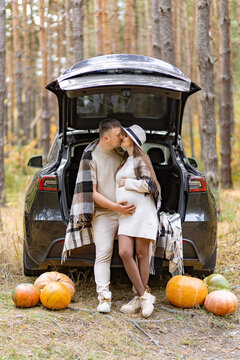 A loving couple shares a tender moment during their maternity photoshoot in a beautiful forest setting