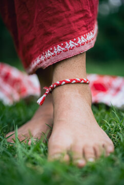 Barefoot person wearing a red and white braided anklet