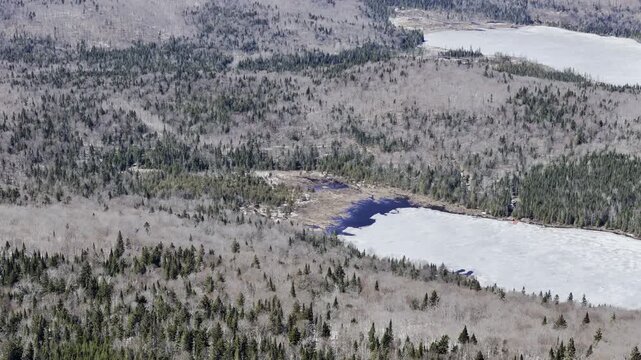 defaultAerial view of winding road along frozen lake in Quebec with forest and mountains under blue sky. g.