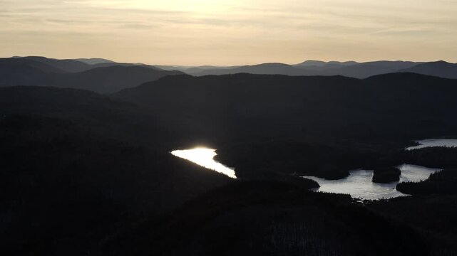 defaultAerial view of winding road along frozen lake in Quebec with forest and mountains under blue sky. g.