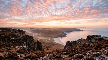 Obraz premium Rocky coastal highland overlooks a winding shoreline beneath a pastel sunrise sky, offering a dramatic natural landscape for travel, geology and outdoor editorial use.