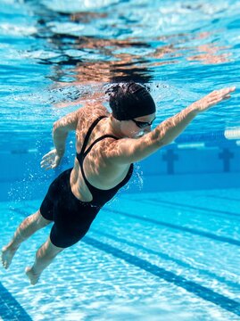 Underwater view of a female swimmer swimming freestyle stroke with bubbles in a swimming pool
