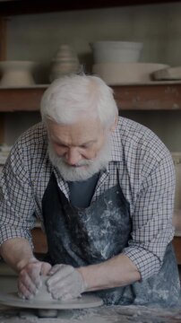 Portrait of experienced artist recording tutorial about pottery working with clay and speaking in workshop. Social media and arts studio concept.