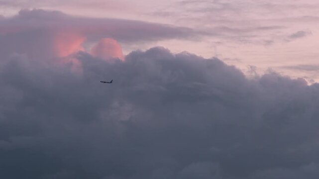 A cinematic video of airplane flying through dramatic storm clouds at sunset creating beautiful pastel sky colors.