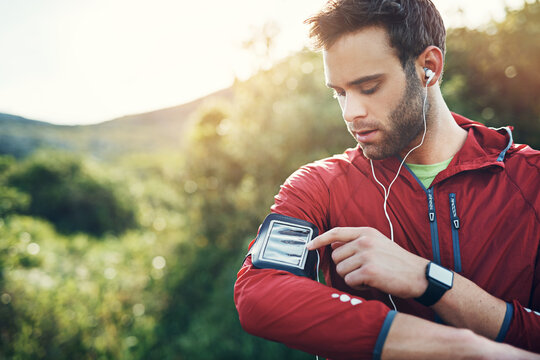Fitness, earphones and man with phone armband, streaming radio and sports playlist in nature. Mobile, runner and male person with music outdoor, listening to audio and exercise song with space