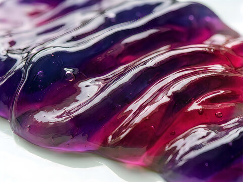 Glossy purple and magenta slime texture spread across white surface in close up view.
