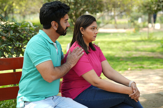 Indian woman feeling depressed after having a argument with her husband at park outdoor. Unhappy Indian couple, Marriage in crisis. Husband and wife problems and extramarital affairs relationship.