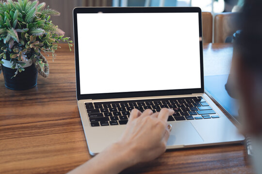 Mockup laptop with blank screen, woman working on laptop on wooden desk, remote work in workspace concept. Close up