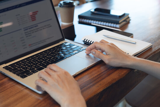 Close up of hands typing on laptop with financial charts, remote work and online business analytics concept.