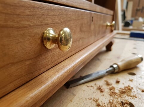restored wooden cabinet Wooden drawer with brass knobs and woodworking chisel on a workbench.