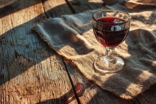 Glass of red wine on rustic wooden table at golden hour