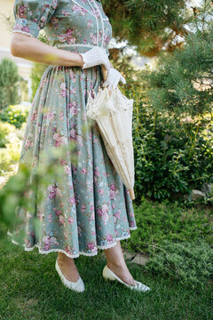 Woman in a vintage floral midi dress holding a folded lace parasol