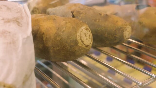 Whole baked jacket potatoes resting on a metal warming rack in a food display.