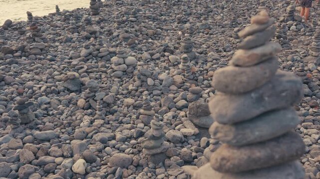 Zen stone stack balancing on pebble beach at sunset cinematic slow motion footage.
