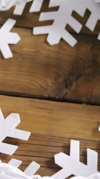 Animation of white crown and snowflakes shapes on wooden table at christmas