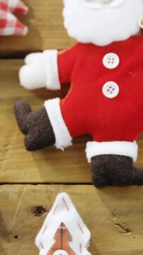 Animation of santa and decorations on wooden background at christmas