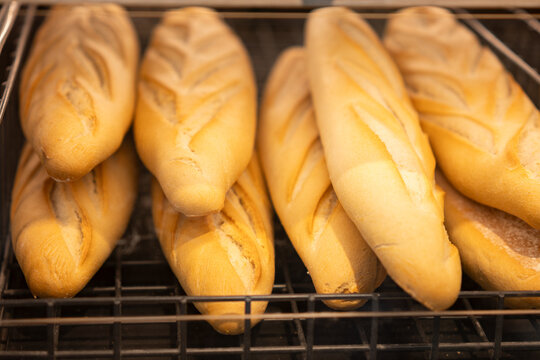 Freshly baked baguettes on a metal rack in a bakery