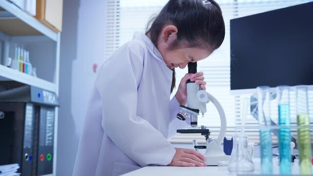 Asian girl student looking through microscope in science laboratory for stem education and biotechnology learning	