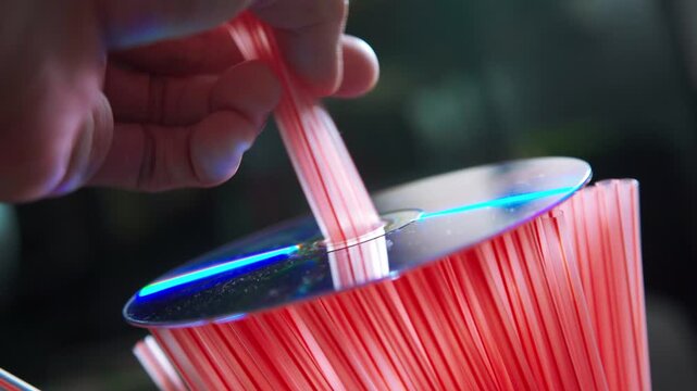 Compact DVD Disc Resting on Plastic Drinking Straws Illustrating Modern Plastic Pollution and Environmental Waste Concept