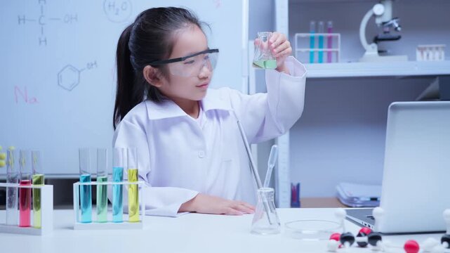 Young asian girl conducting science experiment with colorful liquids in classroom laboratory for education and stem learning concept	