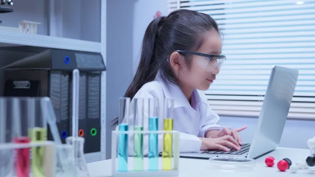 Asian girl student in lab coat using computer in science laboratory for stem education and school learning concepts	