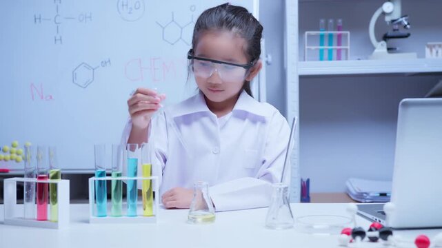 Young asian girl conducting science experiment with colorful liquids in classroom laboratory for education and stem learning concept	