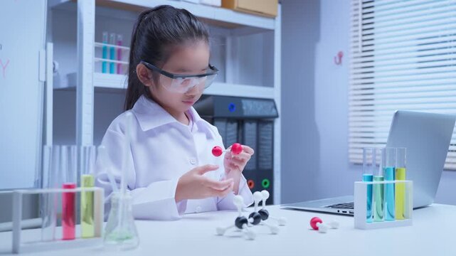 Asian girl student holding chemical molecule model studying science during chemistry lesson in classroom for education and academic development