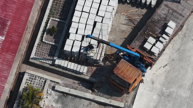 Mobile crane lifting concrete blocks at a construction site during a sunny afternoon