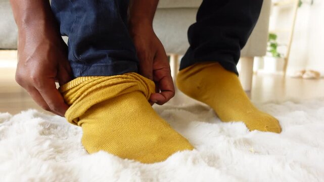 Putting on yellow socks at home on a white rug