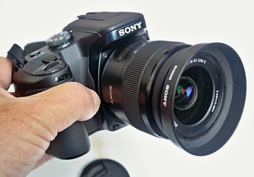 Hand holding Sony digital camera with zoom lens