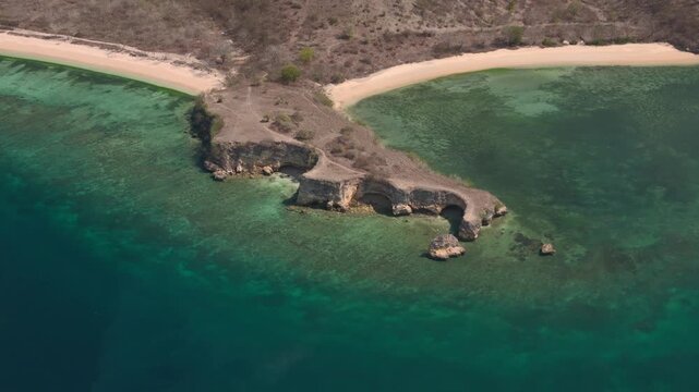 Aerial drone perspective over tropical coastal cliff and crystal turquoise ocean water at sunrise.